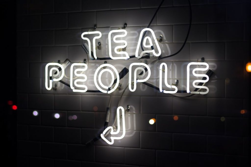 Texte au néon : " Tea people" avec une flèche vers la gauche.