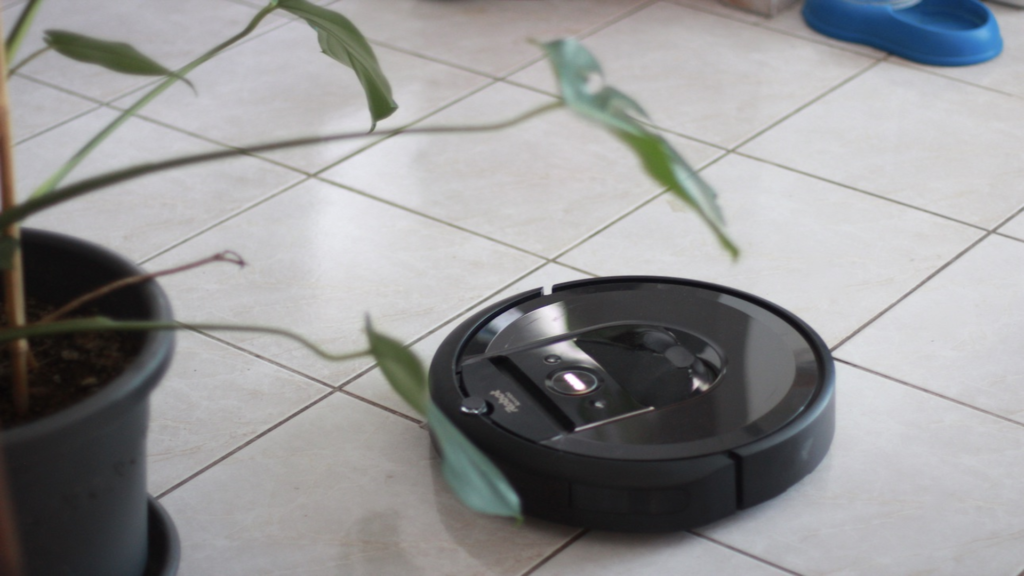 Un robot aspirateur à côté d'une plante.