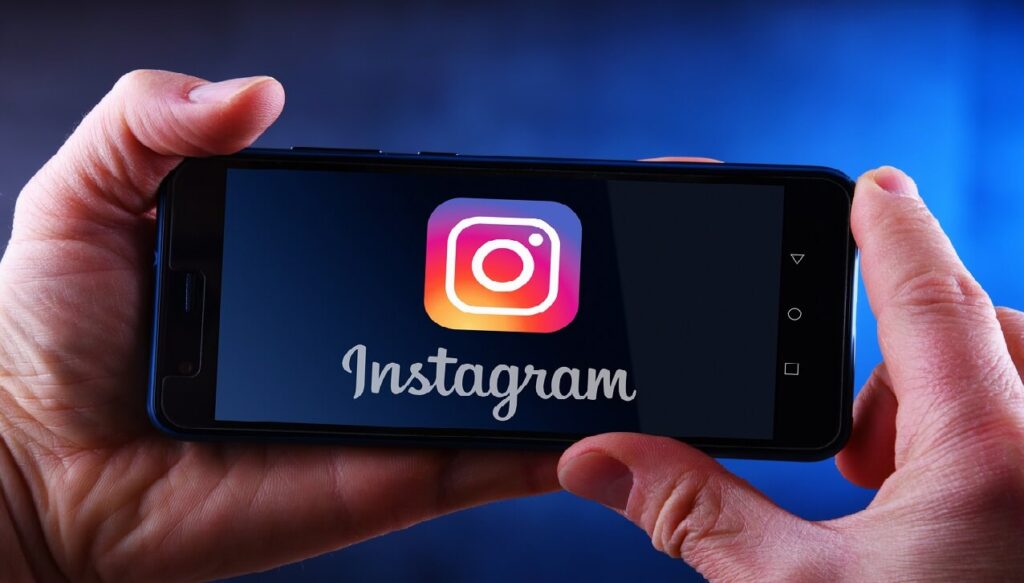 Mains tenant un smartphone affichant le logo d' Instagram