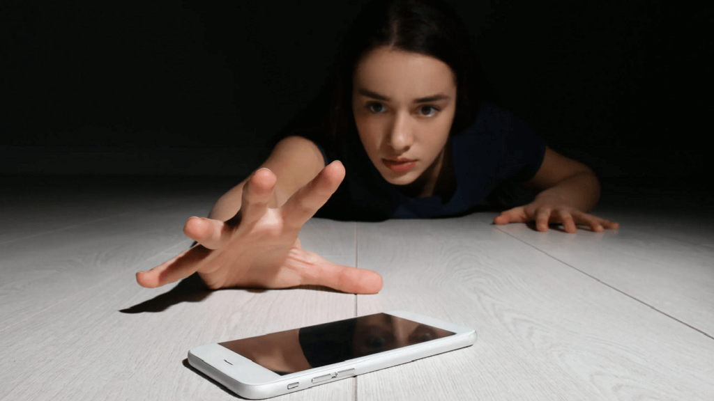 Une adolescente voulant attraper son smartphone à cause de la cyberdépendance