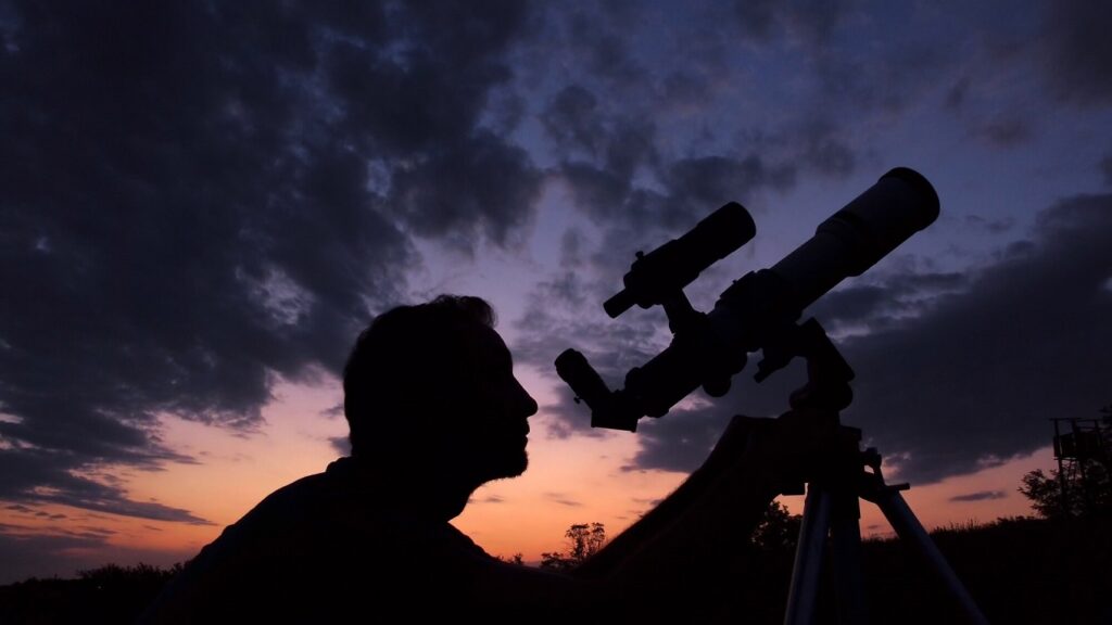 Un homme regardant la constellation d'Orion à travers un télescope
