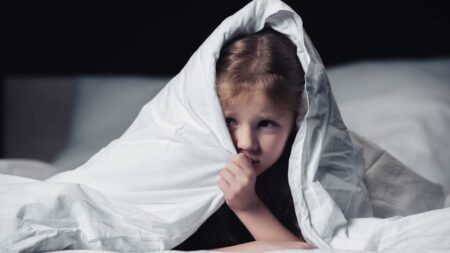 enfant fille cache couette lit