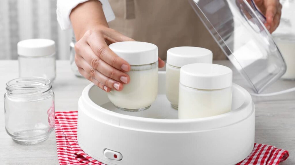 une femme enlève yaourts prets yaourtiere