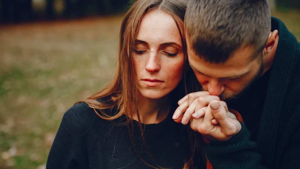 couple homme embrasse main femme songeuse